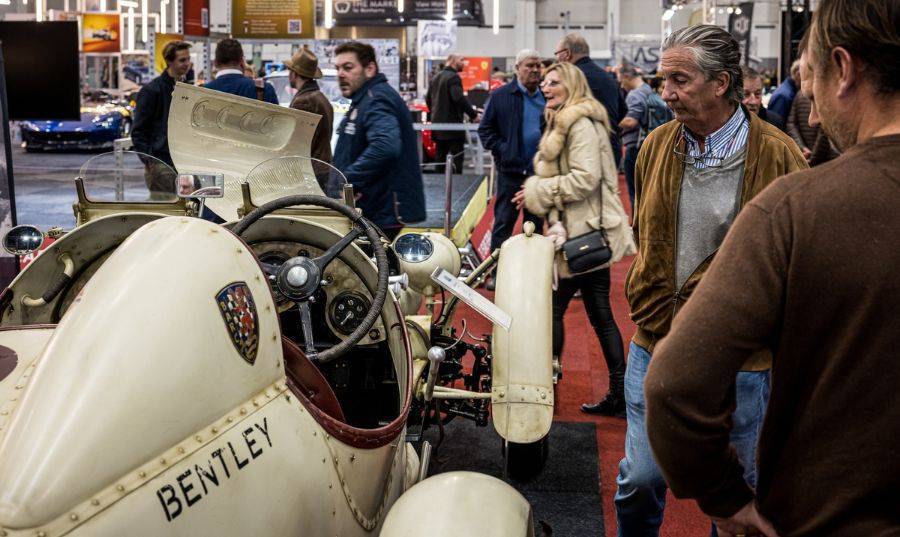 Twee mannen kijken naar een witte klassieke Bentley in de evenementenhal tijdens de Classic Car Show in Brussel